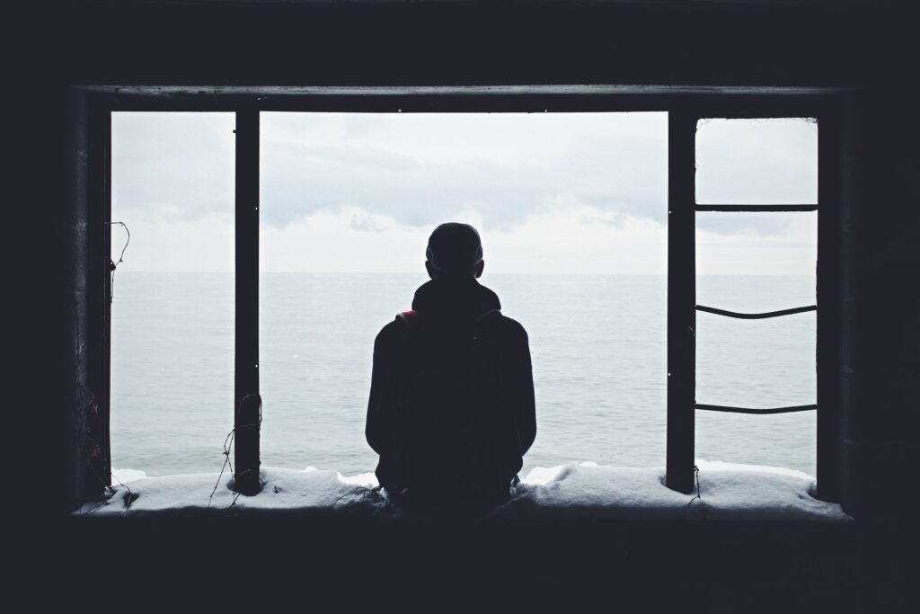 person in a window looking out at sea